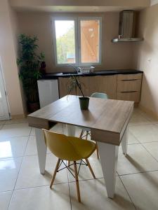 a kitchen with a wooden table and a yellow chair at Calme et nature in Venoy
