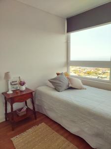 a bedroom with a bed with a window and a table at Despierta con vista al mar en un hogar tranquilo y luminoso in Concón