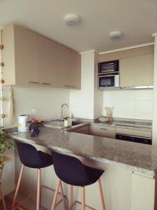 a kitchen with two bar stools and a counter top at Despierta con vista al mar en un hogar tranquilo y luminoso in Concón +2 photos