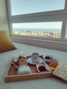 a tray with food on a bed with a window at Despierta con vista al mar en un hogar tranquilo y luminoso in Concón