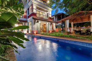 a swimming pool in front of a house at Villa Stairway to Heaven by tisyastays in Candolim