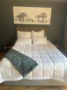 ein großes Bett mit weißen Laken und Kissen in der Unterkunft Sunset Sunrise Country Farm in Komnader