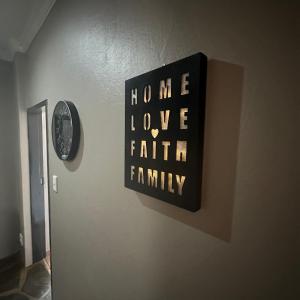Ein Schild mit der Aufschrift „Zuhause, Liebe, Glaube, Familie“ an einer Wand in der Unterkunft Sunset Sunrise Country Farm in Komnader + 50 Fotos