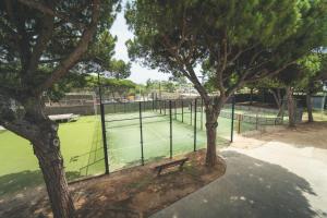 a tennis court with a bench next to two trees at Tres Estrellas Barcelona by HolaCamp in Gavà