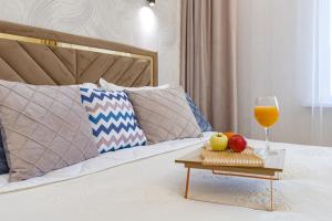 un lit avec un verre de jus d'orange et des fruits sur un plateau dans l'établissement ЖК Поколение, Байтерек, Абу Даби 434, à Astana