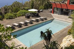 une piscine avec des chaises longues et une maison dans l'établissement Carmim Villa by Cadenzalux, à Biscaia