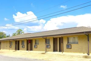 a yellow brick building with windows on a street at Relax Inn by OYO Sulphur Hwy 90 in Sulphur