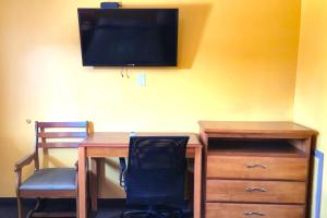 a desk with a chair and a television on a wall at Relax Inn by OYO Sulphur Hwy 90 in Sulphur +11 photos