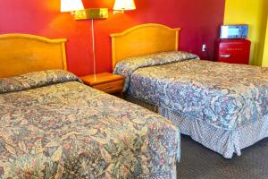 a hotel room with two beds and a red wall at Relax Inn by OYO Sulphur Hwy 90 in Sulphur