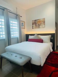 a bedroom with a large white bed with a bench at Rooma Kichi Private Pool in Pantai Cenang