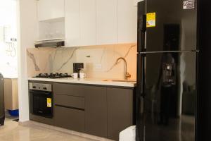 a kitchen with a black refrigerator and a sink at Frente a Viva Envigado, AC, moderno e iluminado in Envigado