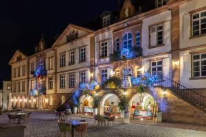 een groep gebouwen 's nachts met blauwe lichten bij Hôtel Val-Vignes Colmar Haut-Koenigsbourg, The Originals Relais in Saint-Hippolyte