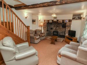 a living room with couches and a stone fireplace at Denhill Cottage in Taunton