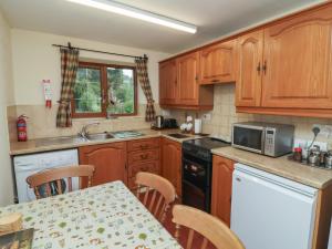 a kitchen with wooden cabinets and a table with chairs at Denhill Cottage in Taunton