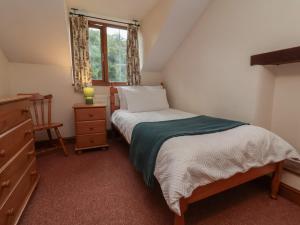 a bedroom with a bed and a dresser and a window at Denhill Cottage in Taunton