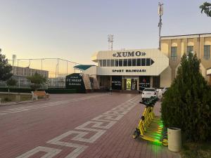 a store with a row of yellow benches in a parking lot at Amiriy hostel in Bukhara