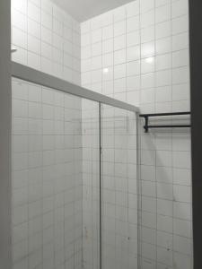 y baño con ducha y azulejos blancos. en Hostel Barra 163, en Salvador