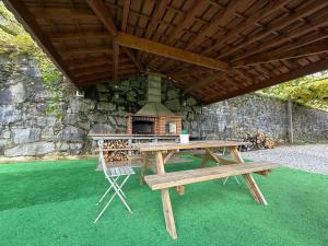 een picknicktafel met een pizzaoven onder een dak bij Sobreiros' Studio - Gerês in Terras de Bouro