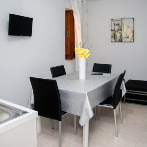 un tavolo da pranzo con sedie e un vaso di fiori di Le Casette di Vita a Sciacca