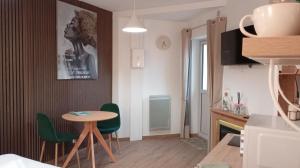 uma pequena cozinha com uma mesa e cadeiras verdes em Le cocon des Rosies le Eleanor Roosevelt em Colleville-sur-Mer