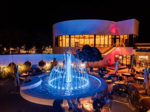 a fountain in front of a building at night at Hotel Pinija in Petrcane