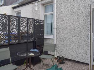 a patio with a table and chairs next to a building at Greens Cottage in Girvan