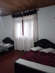 a bedroom with two beds and a window with curtains at Nehara Inn in Nuwara Eliya