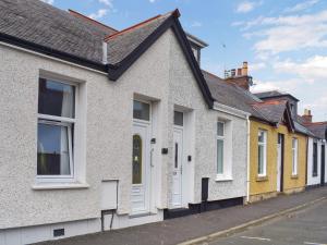 a row of yellow and white houses on a street at Greens Cottage in Girvan +9 photos