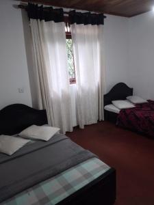 a bedroom with two beds and a window at Nehara Inn in Nuwara Eliya
