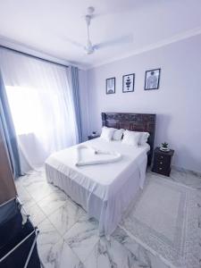 a bedroom with a large white bed with a window at the cozy lookout in Malindi +6 photos