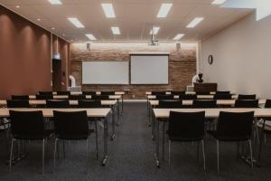 an empty classroom with tables and chairs and a whiteboard at Home Hotel Cardinal in Växjö