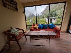 a living room with a couch and a large window at TUMI Villa Salkantay in Colcapampa