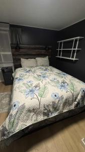 Una cama con un edredón floral en un dormitorio. en Cozy 2-bedroom Downtown Apartment Campbellton Walk to Cafés & Shops, en Campbellton