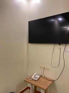 een televisie aan de muur met een telefoon op een tafel bij فندق روز بلازا in Abha +4 foto's