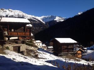 a group of buildings in the snow with mountains at Ourson in Grimentz