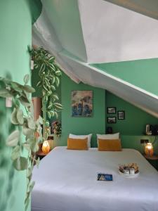 a bedroom with a white bed with a green wall at Le Village Montmartre in Paris