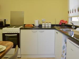 Una cocina con gabinetes blancos y un fregadero. en The Cabin, en Pevensey