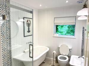 Un baño con bañera, inodoro y lavabo. en Shore House, en Tarbet