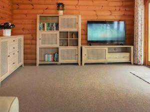 a living room with a television and book shelves at The Lodge in Storrington