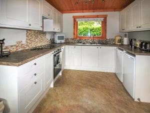 a white kitchen with white cabinets and a window at The Lodge in Storrington