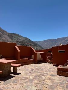 eine Terrasse mit Bänken und Tischen mit Bergen im Hintergrund in der Unterkunft El Patio in Purmamarca