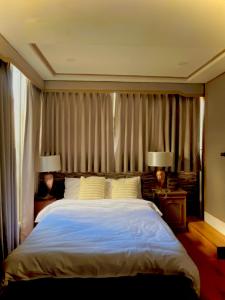 a bedroom with a large bed with two lamps at Hillcrest Boutique Hotel, Reddoors Canley Residential in Manila