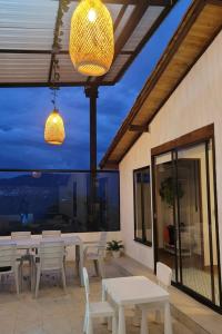 a patio with white tables and chairs and a large window at Manawa Kaona in Somondoco