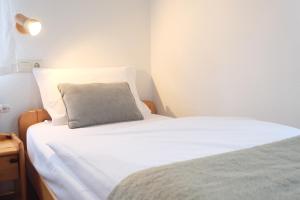 a white bed with a gray pillow on top of it at Pension Berggasse - Parkplatz, Smart-TV & Küche in Olbernhau +71 photos
