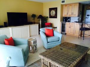 a living room with two chairs and a tv at Midnight Cove II 117F in Siesta Key