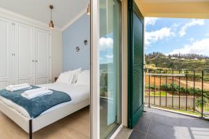 a bedroom with a bed and a balcony with a view at Villa Pargo Green by Madeira Dream Stays in Ponta do Pargo