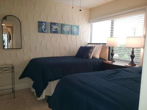 a bedroom with two beds with blue sheets and a mirror at Midnight Cove II 212F in Siesta Key +52 photos