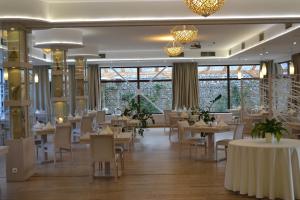 una sala da pranzo con tavoli, sedie e finestre di Hotel Slamený Dom a Košice