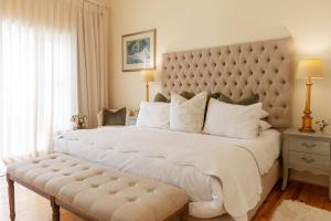 a bedroom with a large white bed with a large padded headboard at Villa Puccini in Cape Town +47 photos