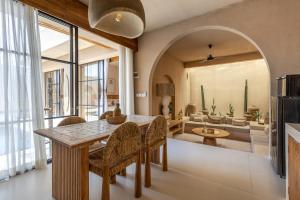Pasir 5 - A stylish 2 bed villa in Bingin w pool في Bingin Beach: مطبخ وغرفة معيشة مع طاولة وكراسي